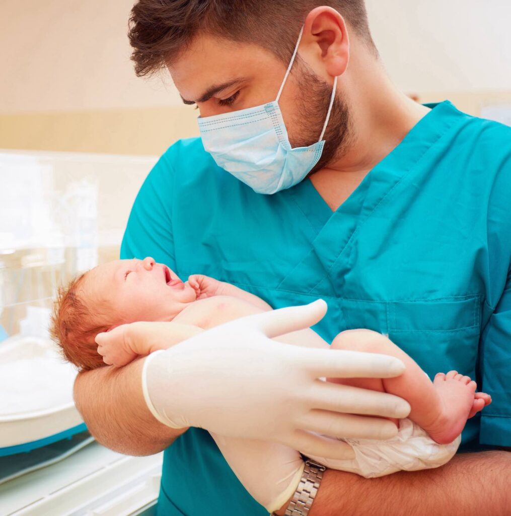 young adult man holding a newborn baby in hospital